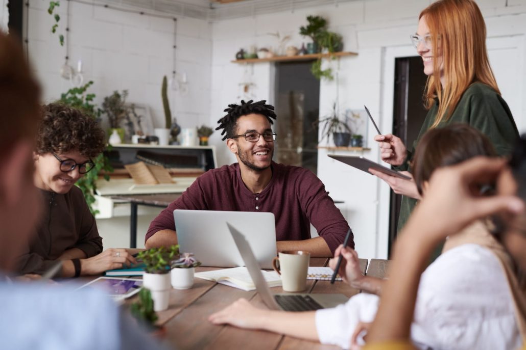 Des employés autour d'une table au bureau lors d'un atelier qui sourient